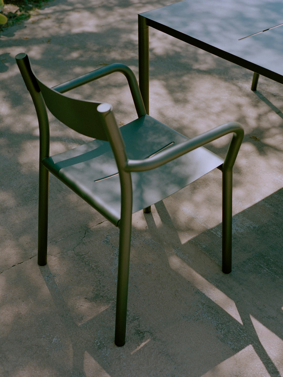 Green chair on a stone patio with a blurred background